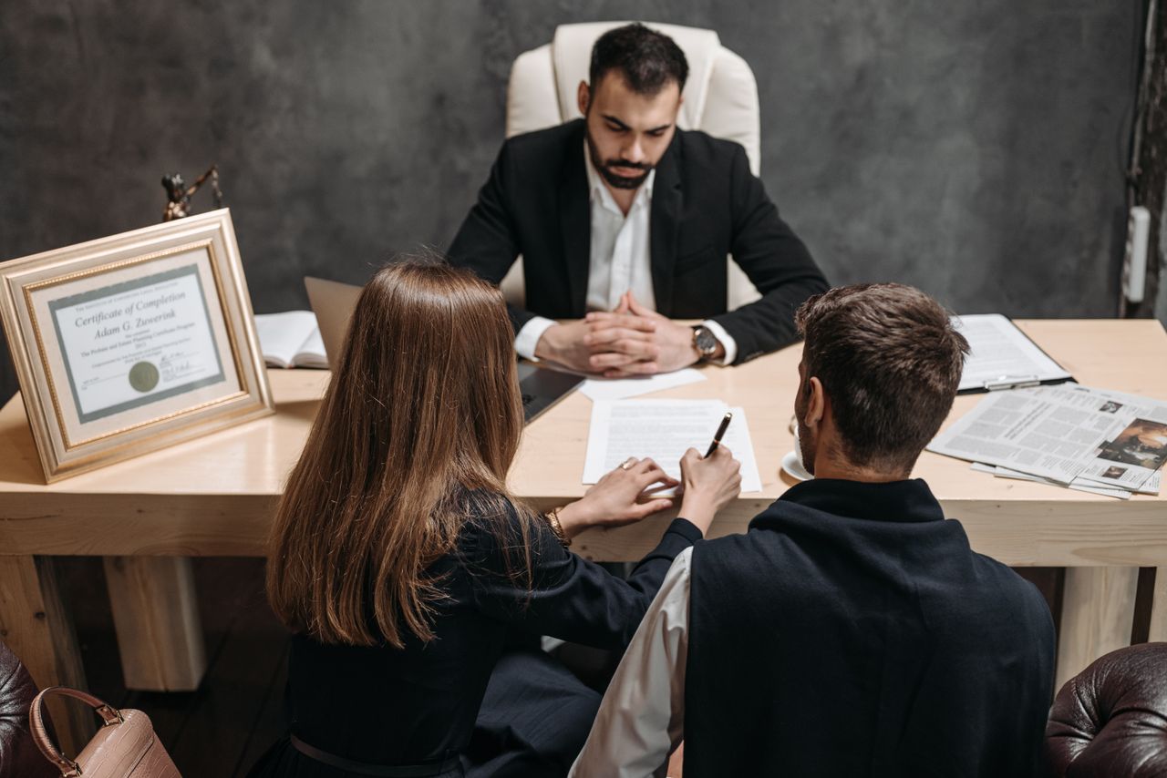 Aree di attività A lawyer discusses legal documents with clients in an office setting.