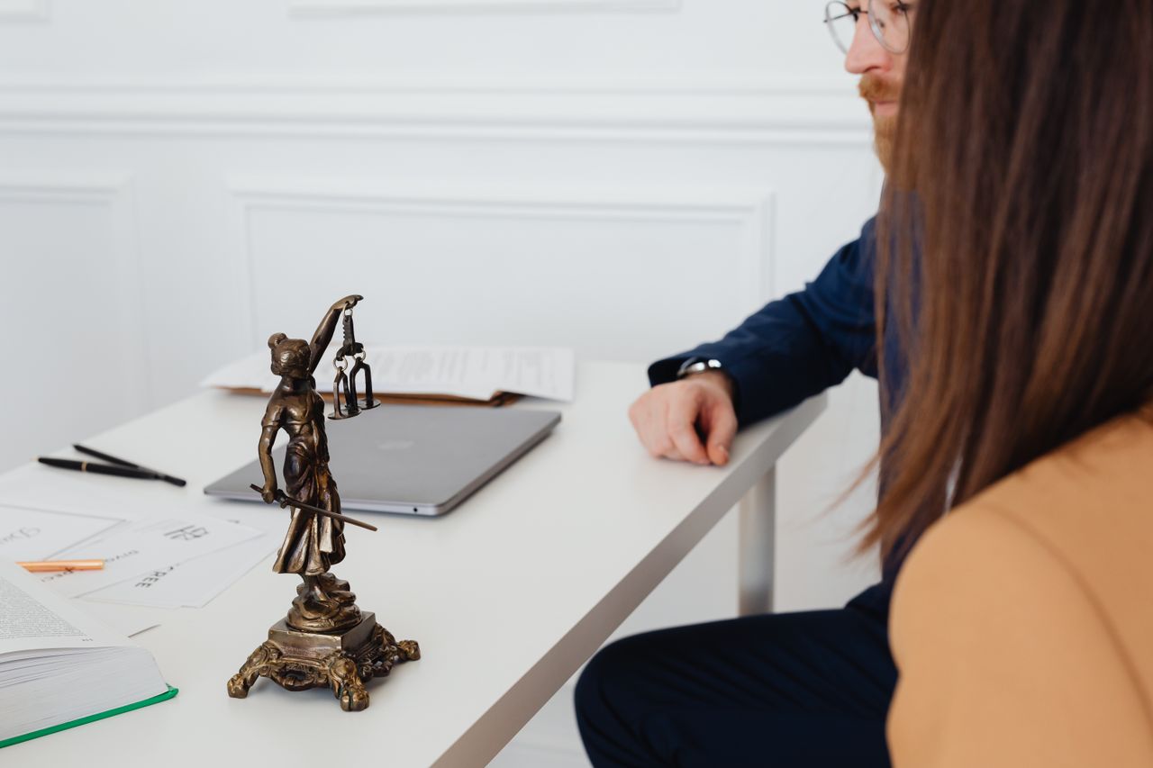 Aree di attività Professional setting with lawyers and Lady Justice statue discussing legal documents.